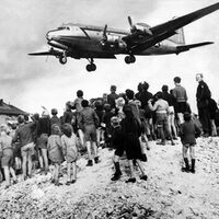Amerikanische Flugzeuge werfen während der Blockade Berlins Lebensmittel und Vorräte in der Nähe einer Menschenmenge von Berlinern ab