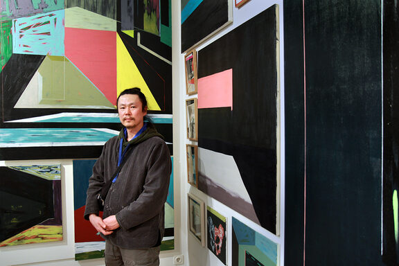 Das Bild zeit den Künstler Bongjun OH vor seinen Kunstwerken.
