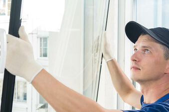 Das Bild zeigt einen Mann, der ein neues Fenster einsetzt.