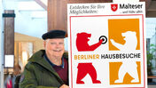 Ein Mann mit Mütze macht Werbung für die Plakatkampagne „Berliner Hausbesuche“